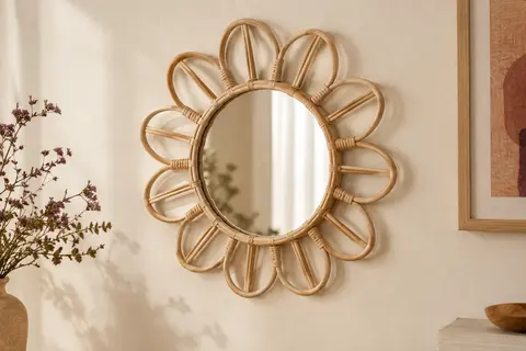 Miroir mural rond en rotin beige à silhouette florale, présenté sur un mur crème.