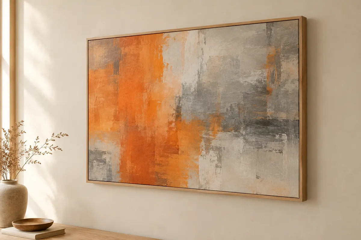 Toile murale abstraite orange et grise au format horizontal, montée sur un cadre en bois, sur un mur crème.