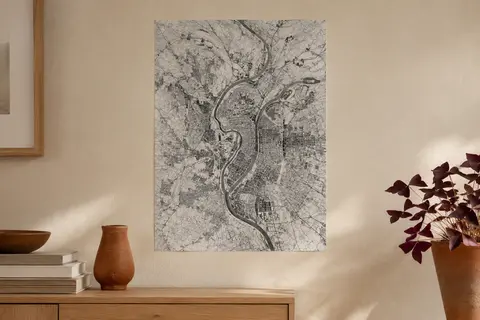 Affiche cartographique de Lyon en noir et blanc, au format A3, présentée sur un mur crème.